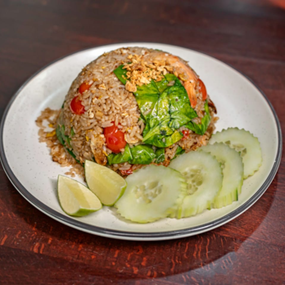 Ayuthaya Thai Cuisine's fried rice with shrimp, tomatoes, greens, and crispy garlic, garnished with lime and cucumber.